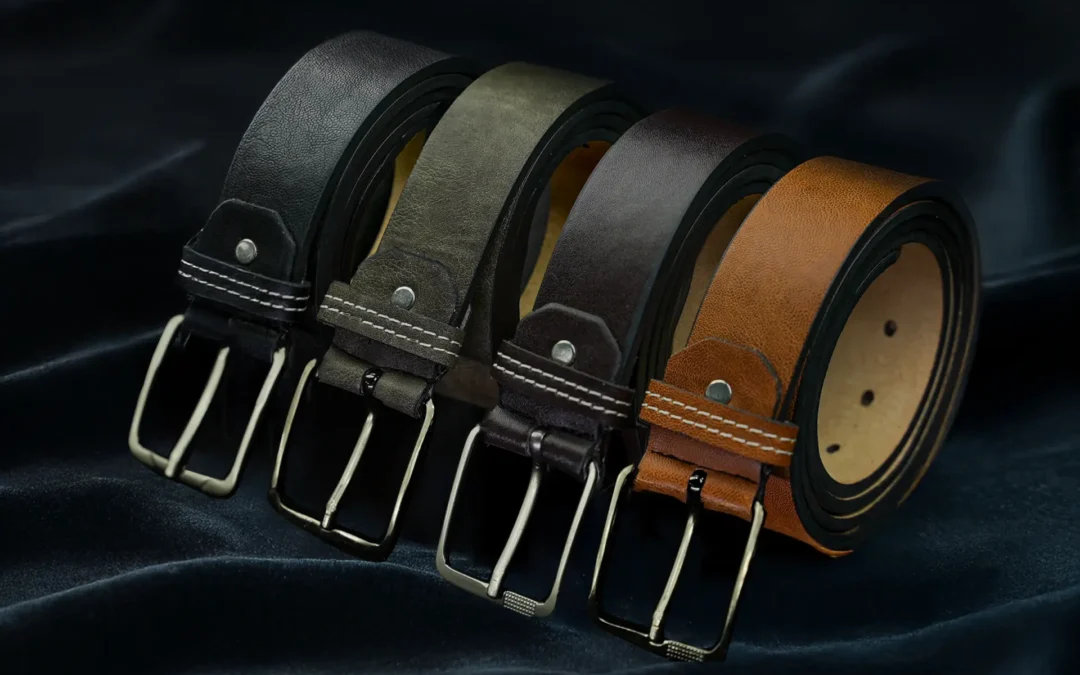 Leather belts in black, grey, brown and tan on a fabric background