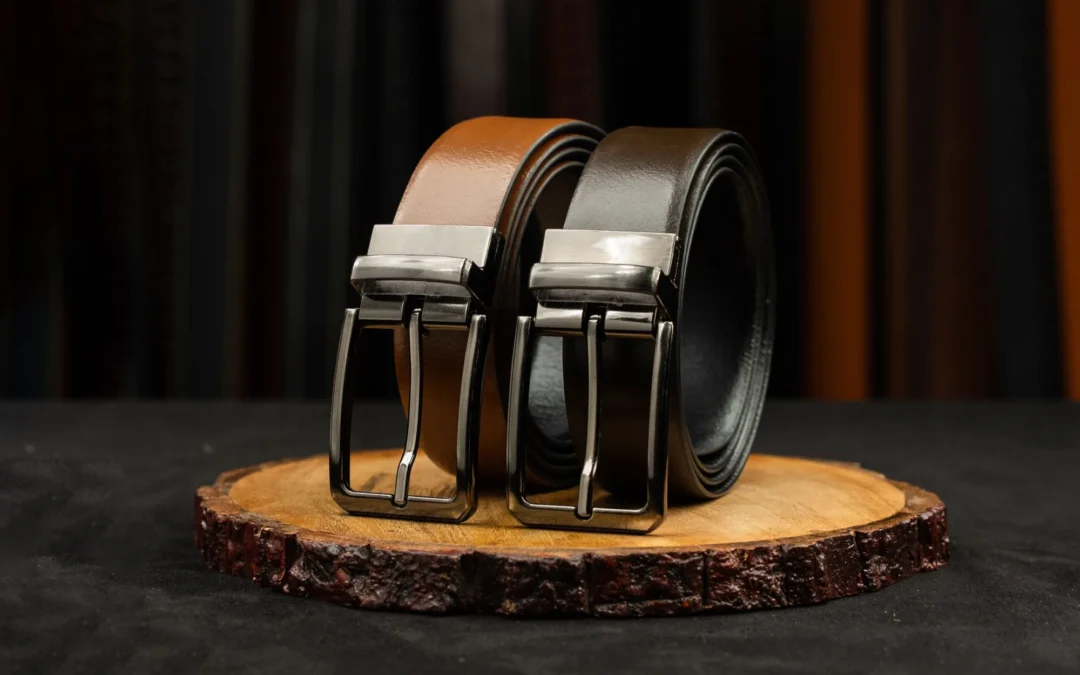 Two leather belts with metal buckles displayed on a rustic wooden platform